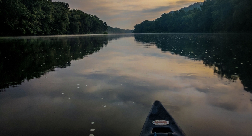 The tip of a canoe appears in the foreground, resting on calm water that reflects the sky.